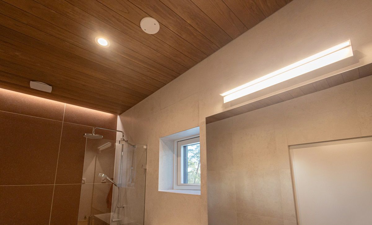 L'illuminazione del locale doccia è costituita da un'applique BLADE600 sullo specchio, da downlight a soffitto e da una striscia LED a illuminazione indiretta nella scanalatura del soffitto sulla parete principale vicino alla doccia.
